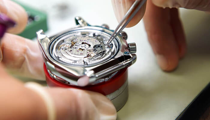 Seseorang sedang memperbaiki komponen mesin jam tangan
